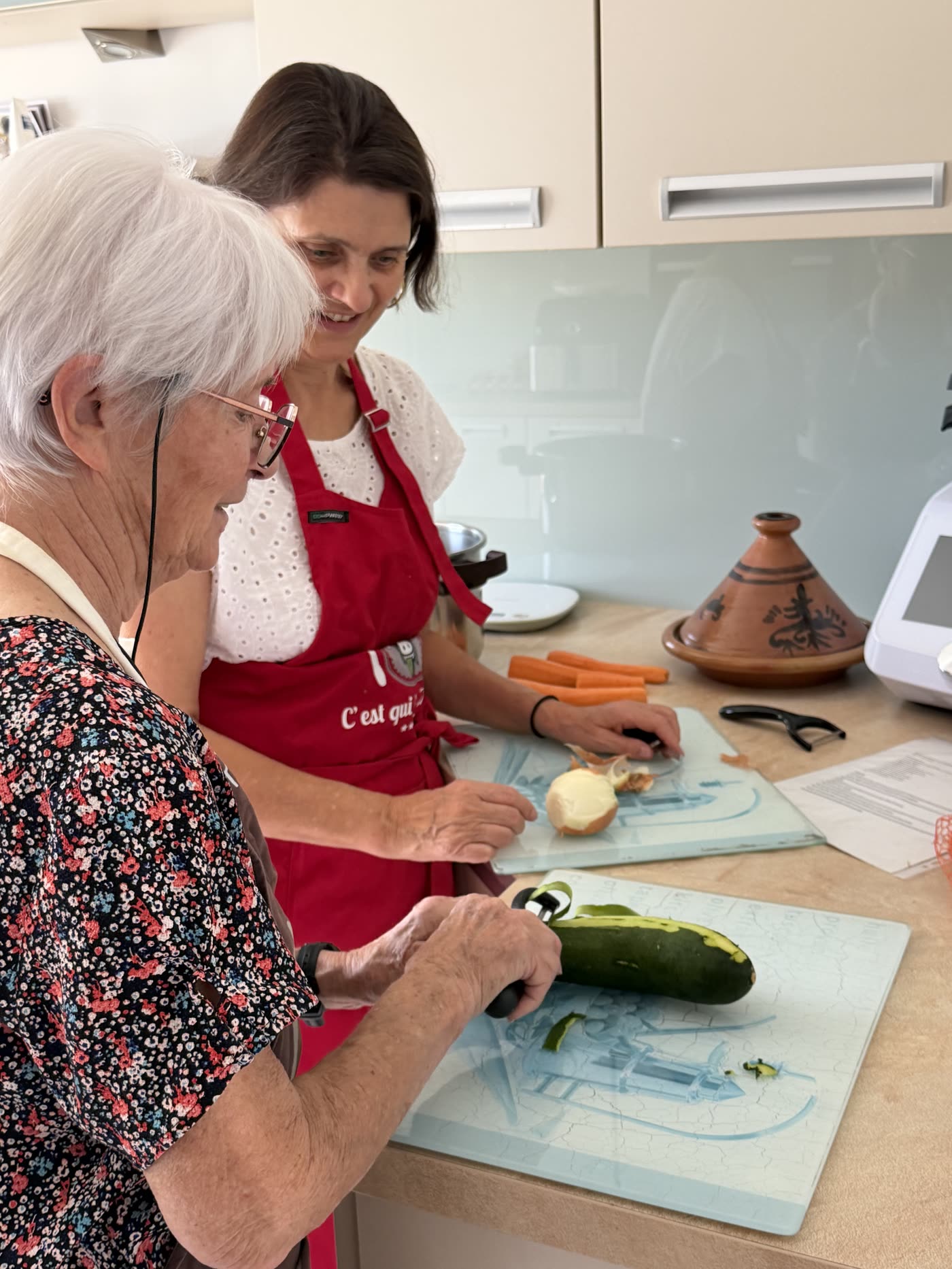 Une aide-soignante prépare un repas avec une personne âgée dans une cuisine chaleureuse